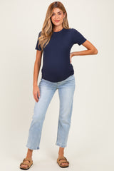 woman wearing a navy blue ribbed short sleeve maternity top and light blue jeans, showing her baby bump