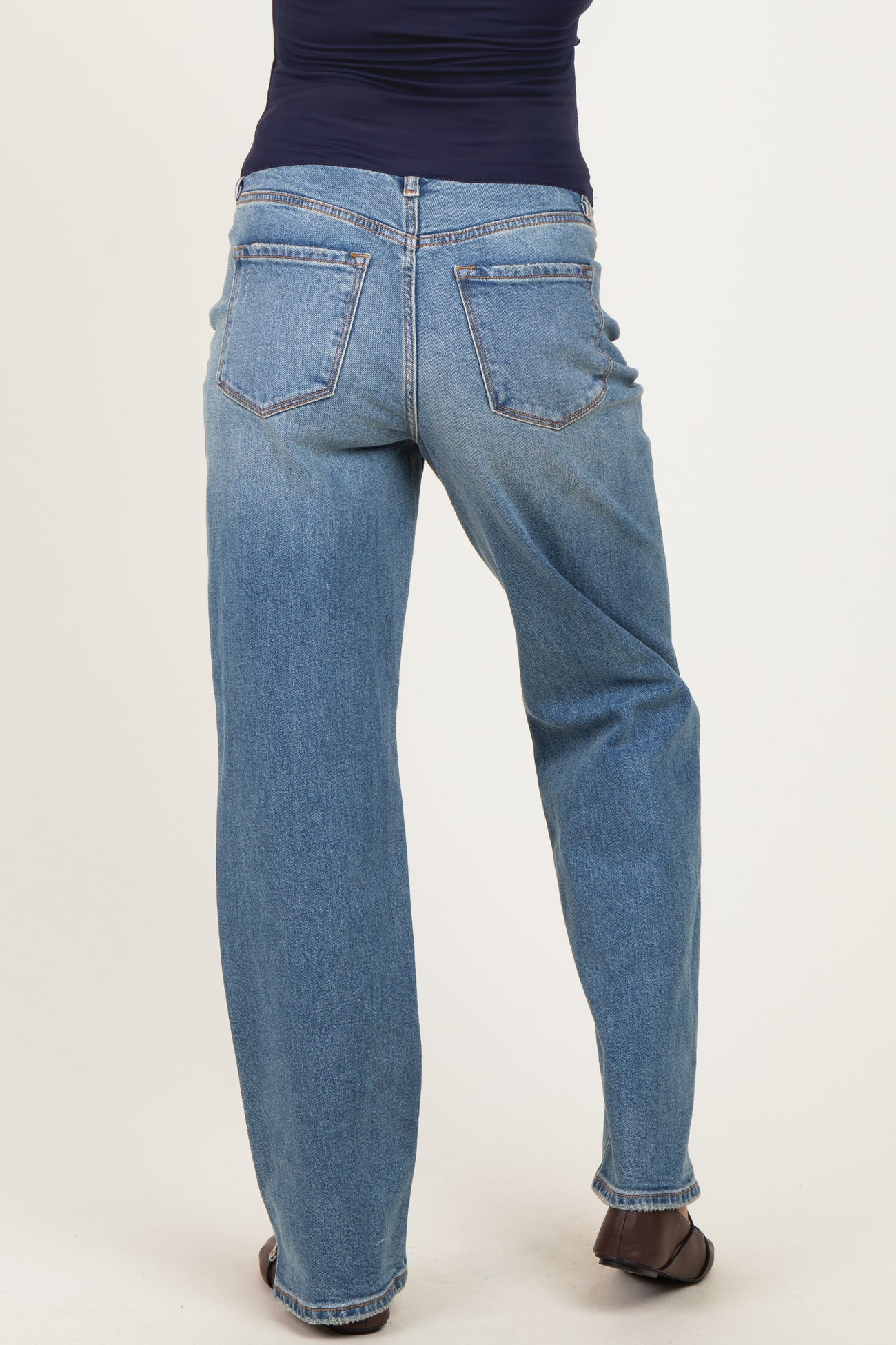 woman wearing blue maternity jeans, showing the back view with a relaxed fit and five-pocket style