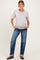 woman wearing a light gray short sleeve maternity top and blue rolled hem jeans, showing her baby bump