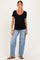 woman wearing a black maternity top with a scalloped neckline and paired with distressed light blue jeans