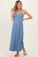 woman wearing a light blue maternity dress with button details and spaghetti straps, showing a baby bump