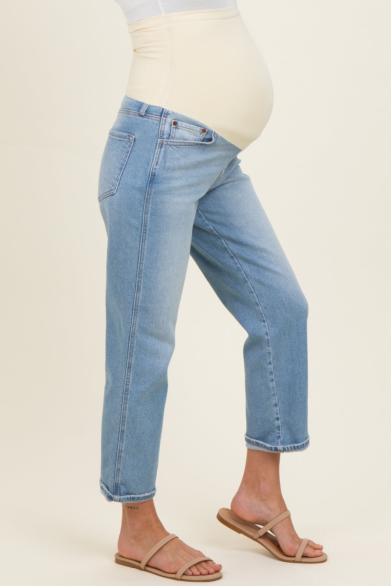 woman wearing light blue maternity jeans with a stretchy beige panel and a visible baby bump