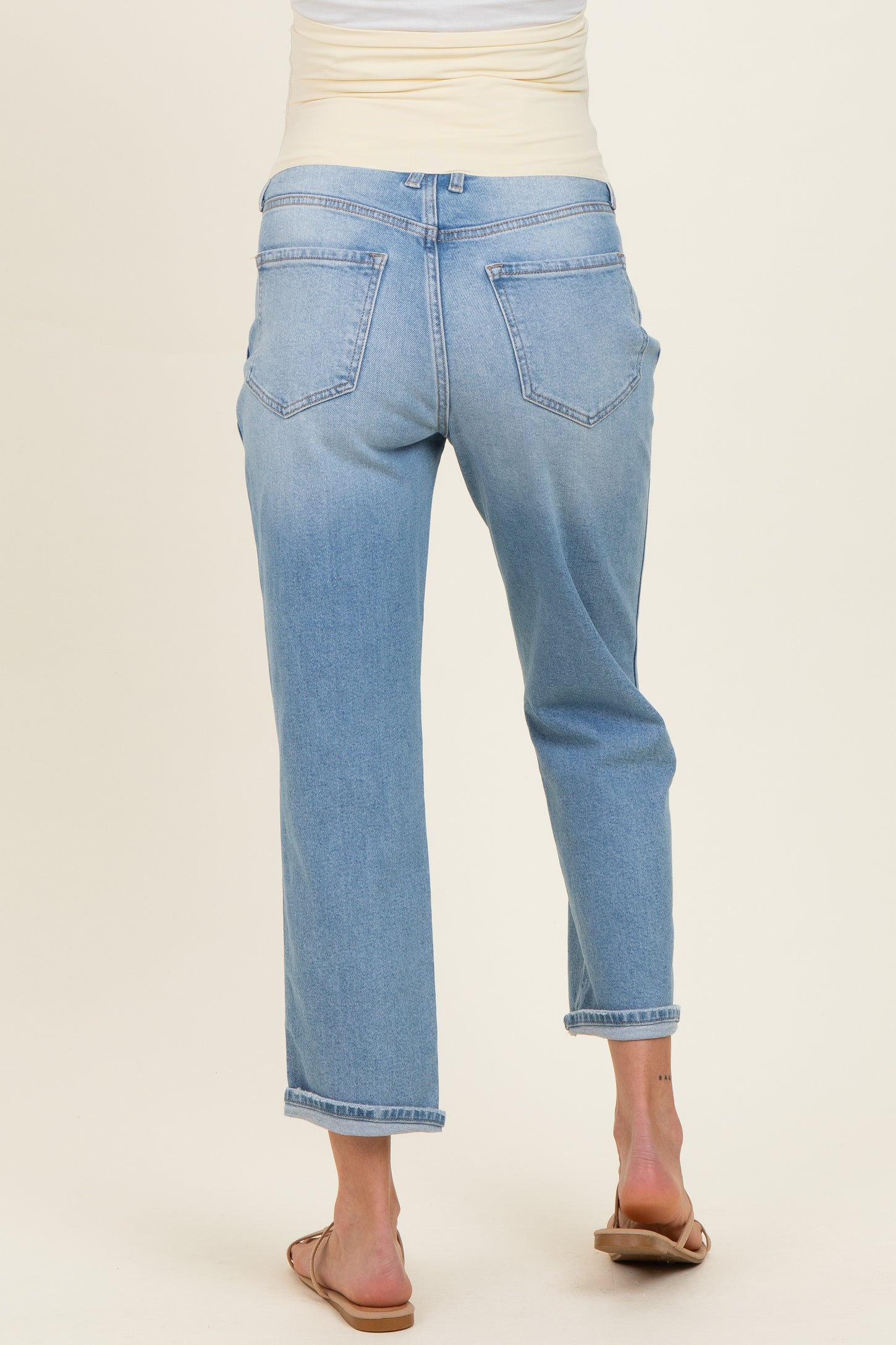 woman wearing light wash maternity jeans with a relaxed fit and rolled cuffs, showing the back view