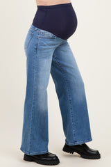 woman wearing light blue wide-leg maternity jeans with a dark blue over-the-bump panel and visible baby bump