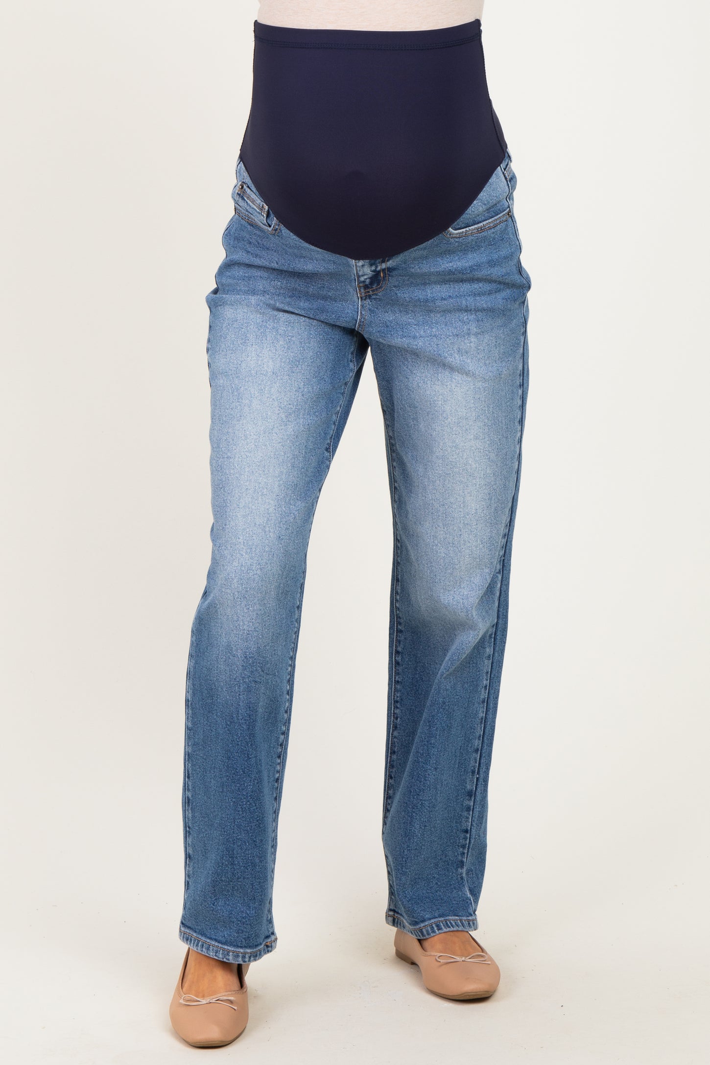 woman wearing a pair of light blue maternity jeans with a navy over-the-bump panel and a straight leg cut