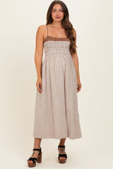 woman wearing a brown and white gingham maternity dress with smocked bodice and adjustable spaghetti straps