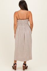 woman wearing a brown and cream checked maternity maxi dress with a smocked back and adjustable straps