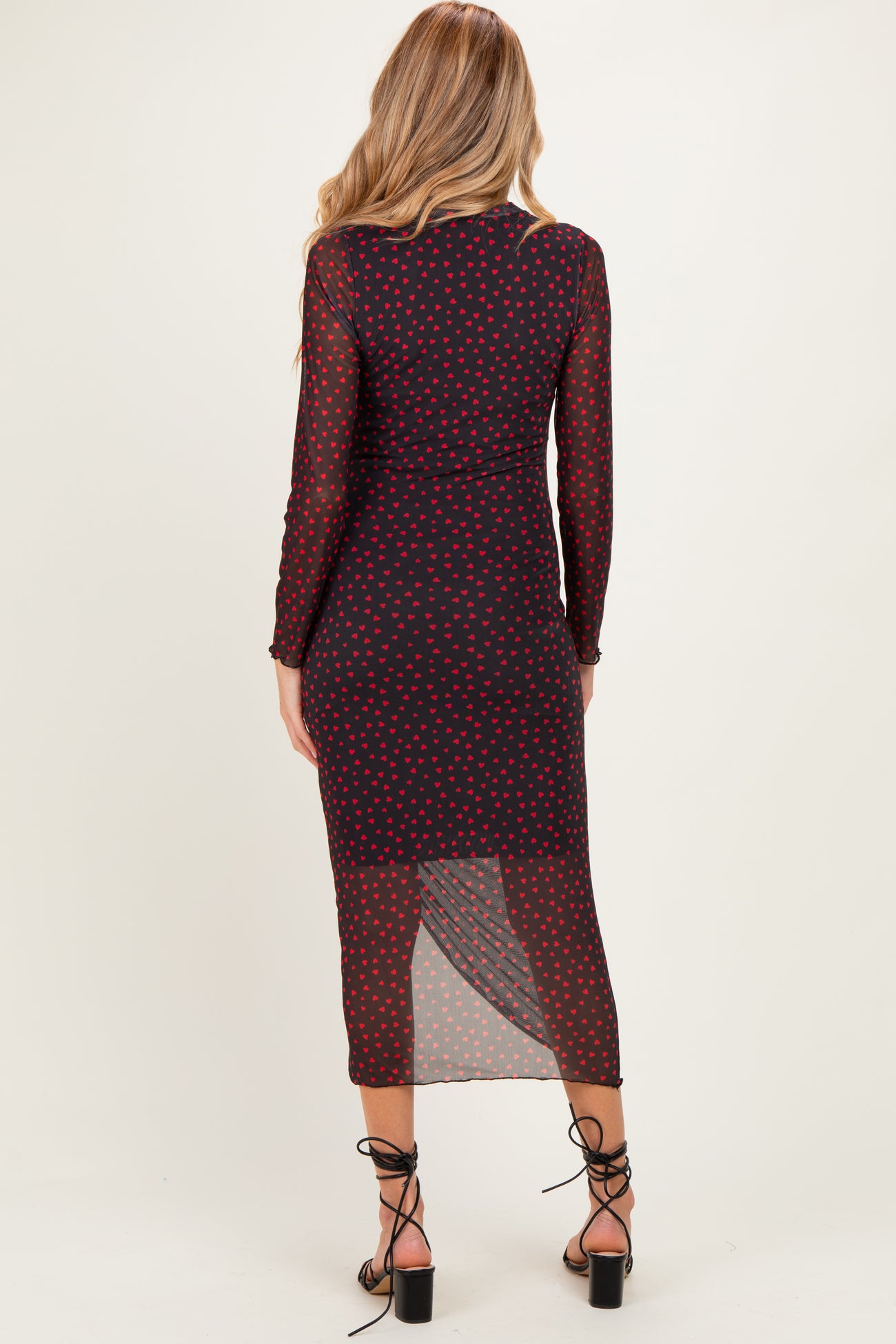 woman wearing a black maternity dress with red polka dots and long sleeves, seen from the back