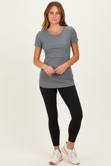 woman wearing a gray short sleeve fitted top with a round neck and black leggings, standing with hands on her hips