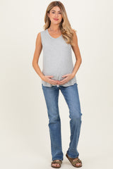 woman wearing a grey sleeveless maternity top and holding her baby bump, paired with blue jeans and sandals