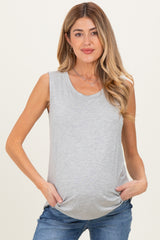 woman wearing a gray sleeveless maternity top and showing her baby bump while standing in jeans