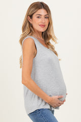 woman wearing a gray sleeveless maternity top and holding her baby bump
