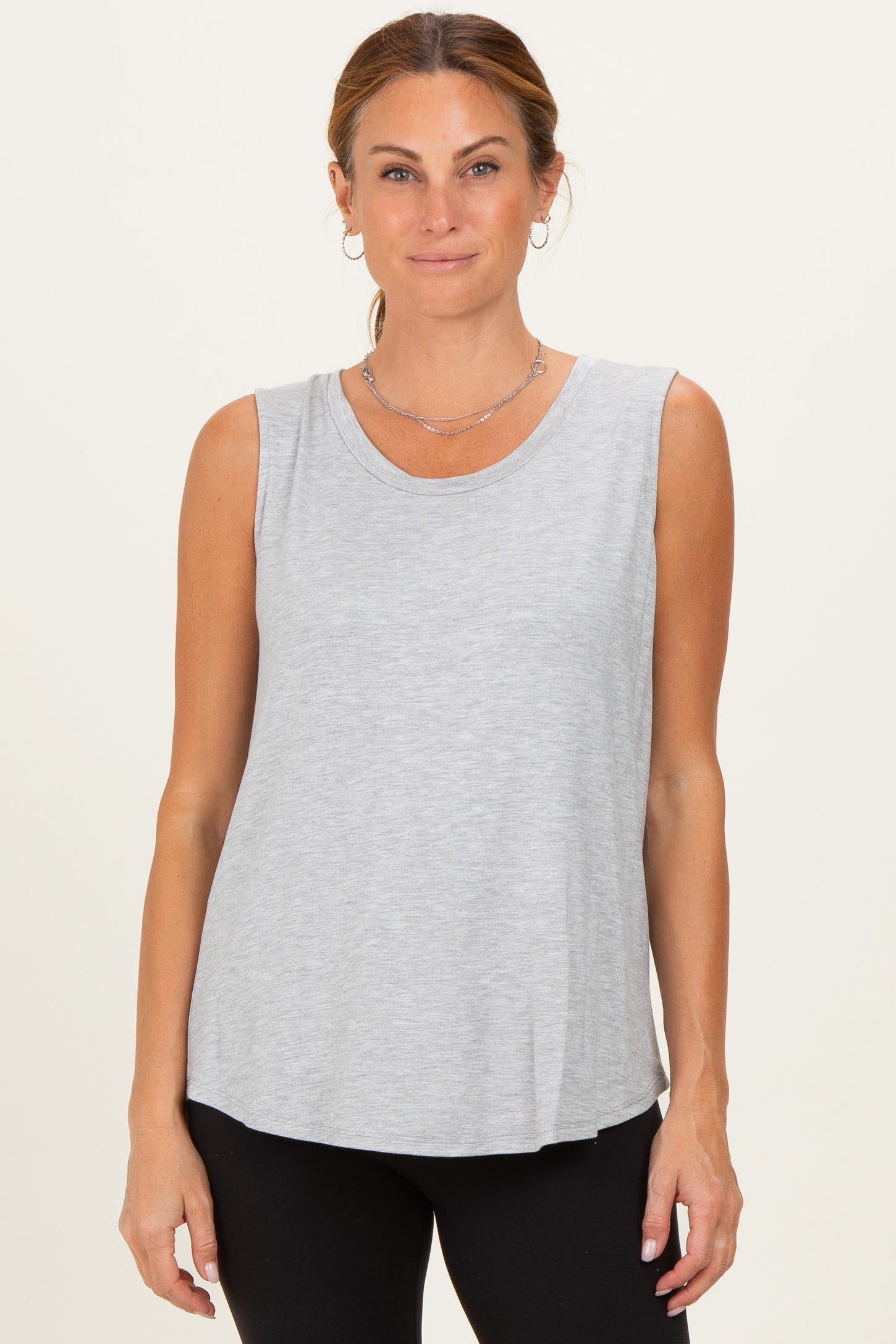 woman wearing a light gray sleeveless top with a rounded neckline and relaxed fit, styled with black leggings