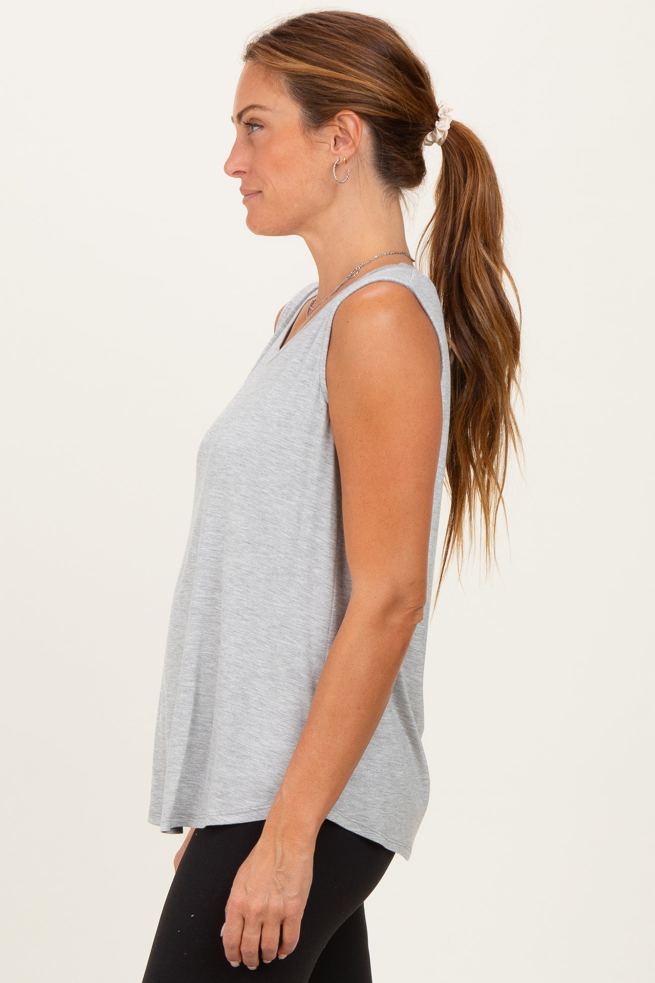 woman wearing a gray sleeveless top with a relaxed fit and side slits, paired with black leggings