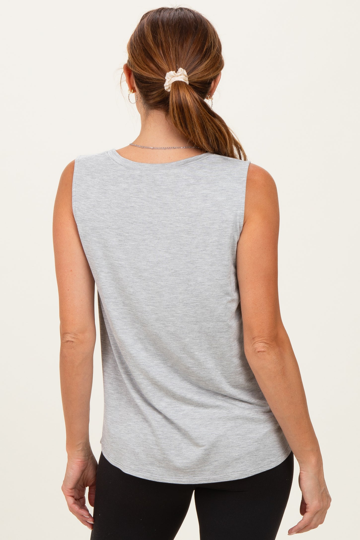 woman wearing a gray sleeveless top, seen from the back, with her hair tied up