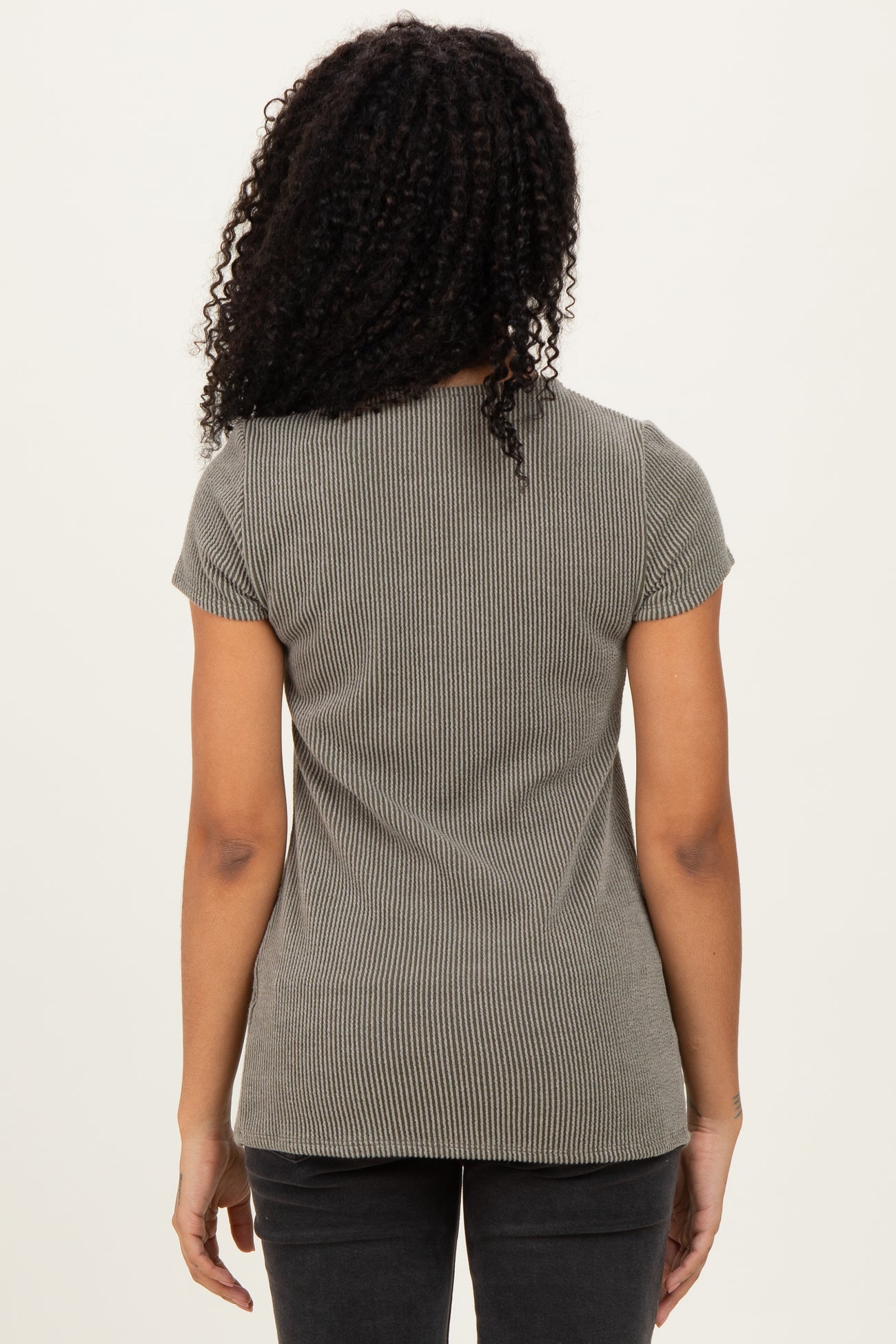 woman wearing a grey ribbed short sleeve top, viewed from the back, paired with black jeans
