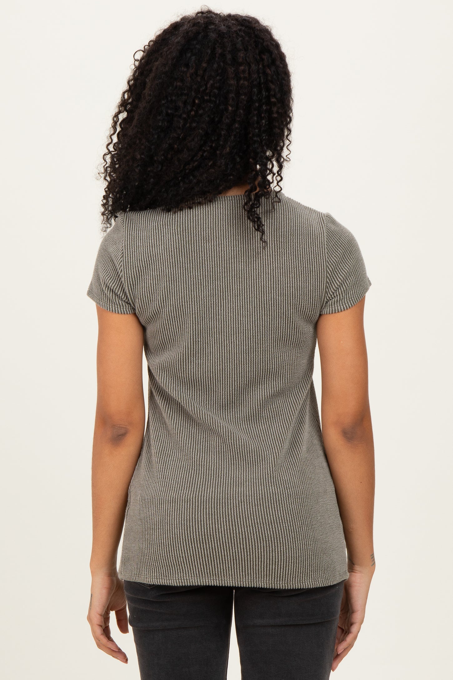 woman wearing a grey ribbed short sleeve top, viewed from the back, paired with black jeans