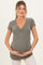 woman wearing a grey ribbed maternity top with a v-neck and short sleeves, holding her baby bump