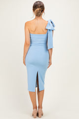 woman wearing a light blue one-shoulder maternity dress with a bow detail on the sleeve and a back slit