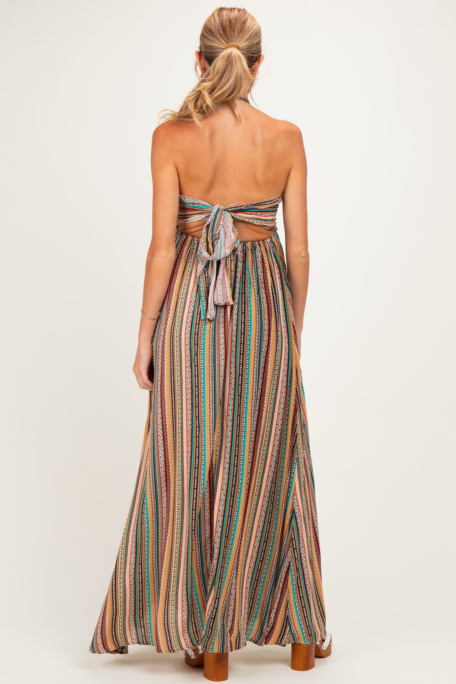 woman wearing a multicolor striped maxi maternity dress with a back tie detail and open back