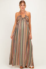 woman wearing a multicolored striped maternity maxi dress with a halter neck and flowing silhouette, showcasing her baby bump