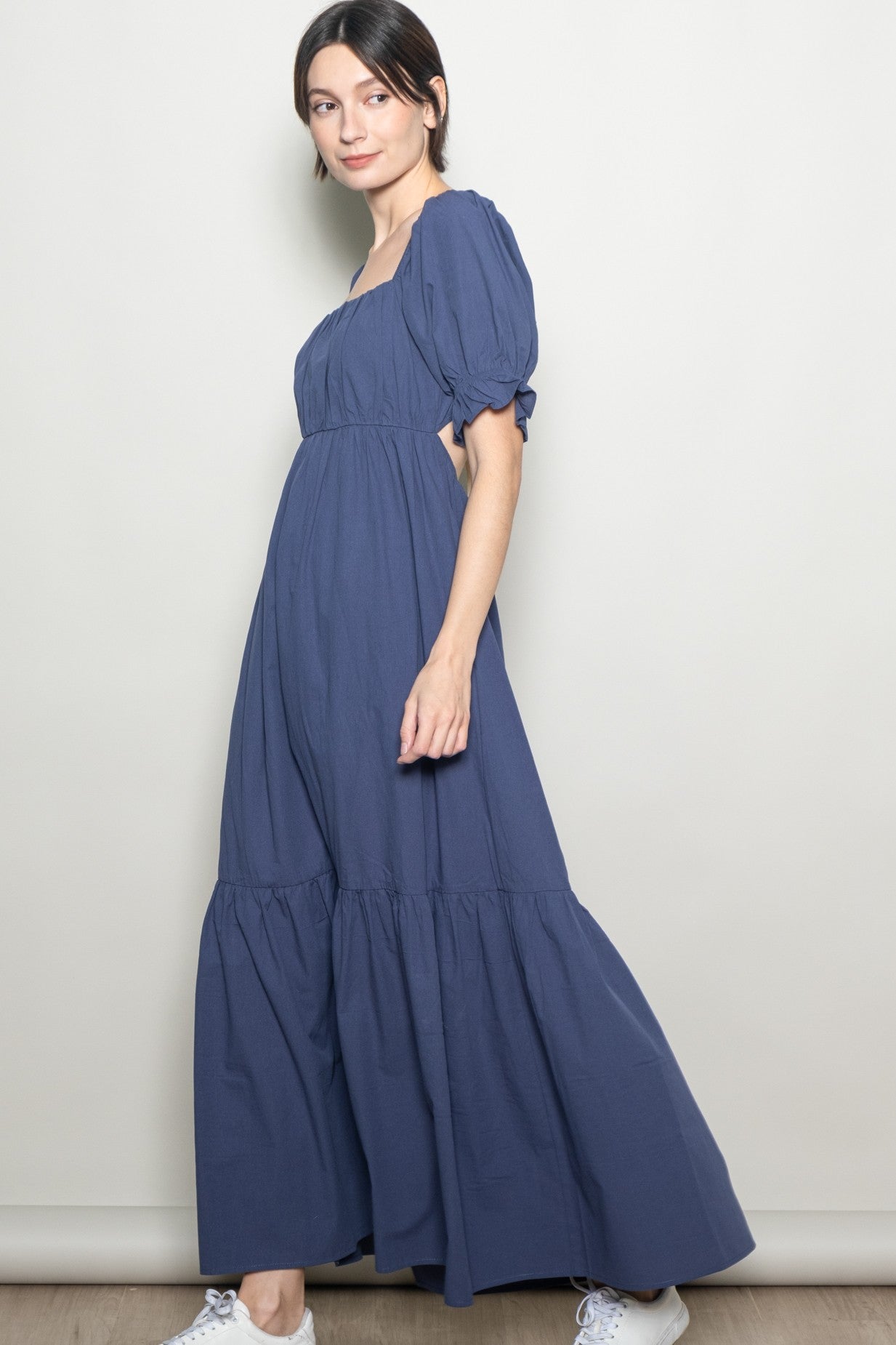 woman wearing a navy blue maxi dress with puff sleeves and a tiered hemline