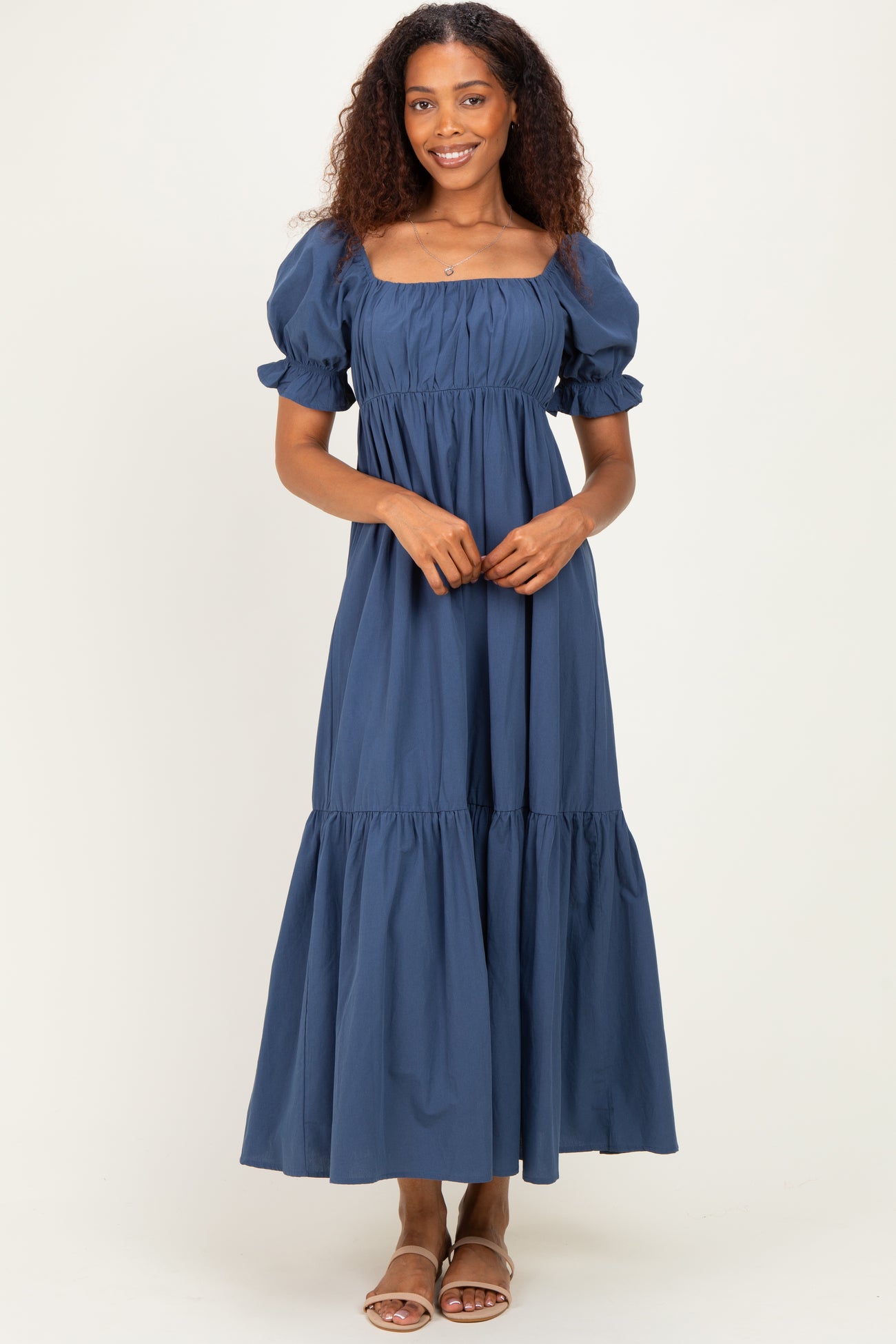 woman wearing a navy blue puff sleeve maxi dress with a square neckline and tiered skirt