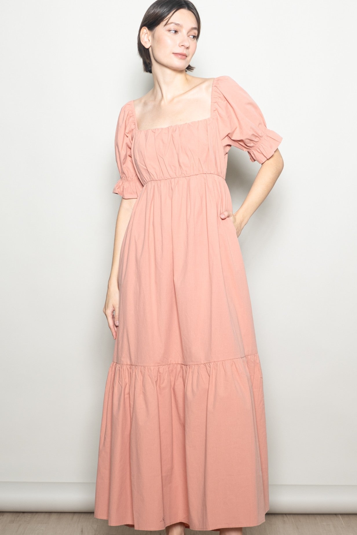woman wearing a pink puff sleeve maxi dress with a square neckline and tiered skirt