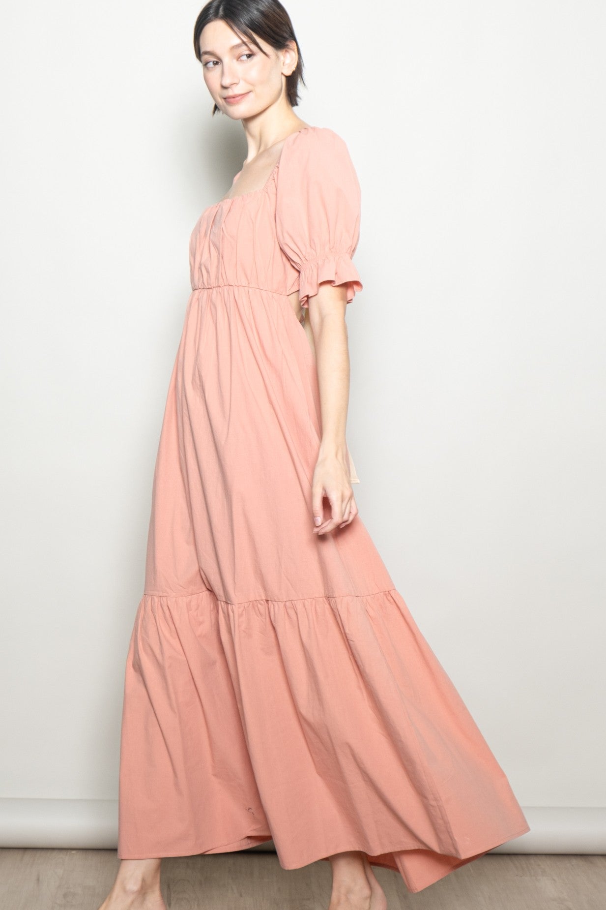 woman wearing a light pink puff sleeve maxi dress with a ruffled hem and square neckline