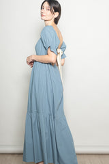 woman wearing a blue maxi dress with puff sleeves and a bow detail on the back