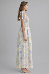 woman wearing a floral maxi dress with adjustable tie straps and a smocked bodice in pastel colors