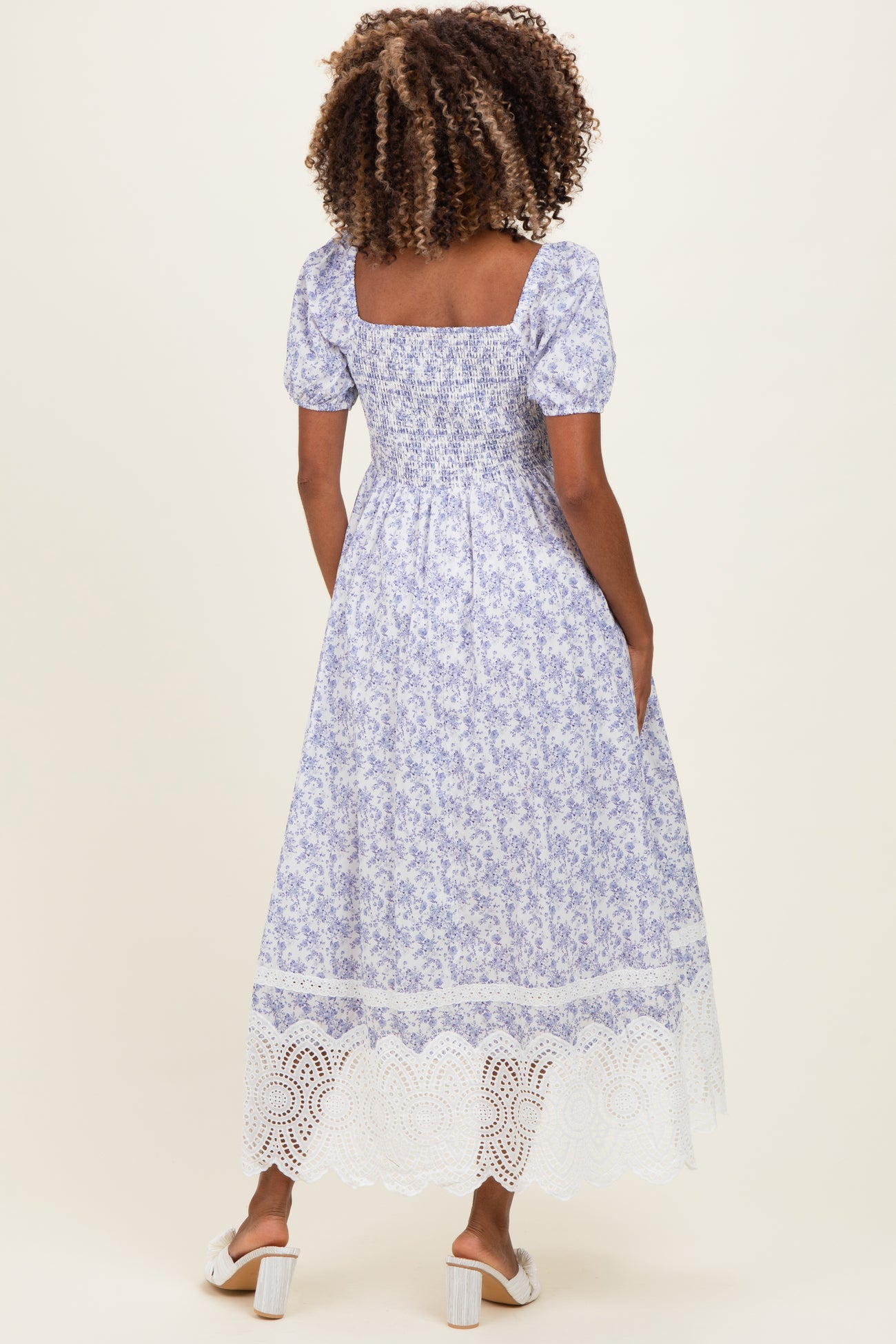 woman wearing a purple floral maternity maxi dress with short puff sleeves and a lace trim hem
