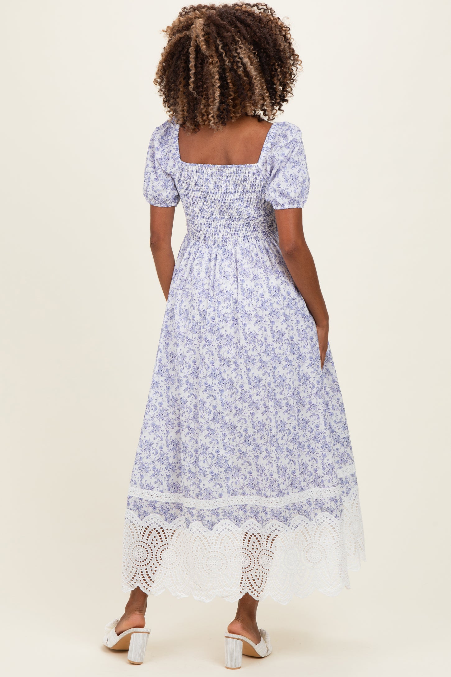 woman wearing a purple floral maternity maxi dress with short puff sleeves and a lace trim hem