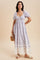 woman wearing a lavender floral maxi dress with short puff sleeves and lace trim at the hem, holding a straw hat