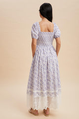woman wearing a lavender floral square neck maxi dress with puff sleeves and a lace trim hem