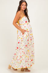woman wearing a white floral maternity maxi dress with pockets and a yellow trim, showing her baby bump