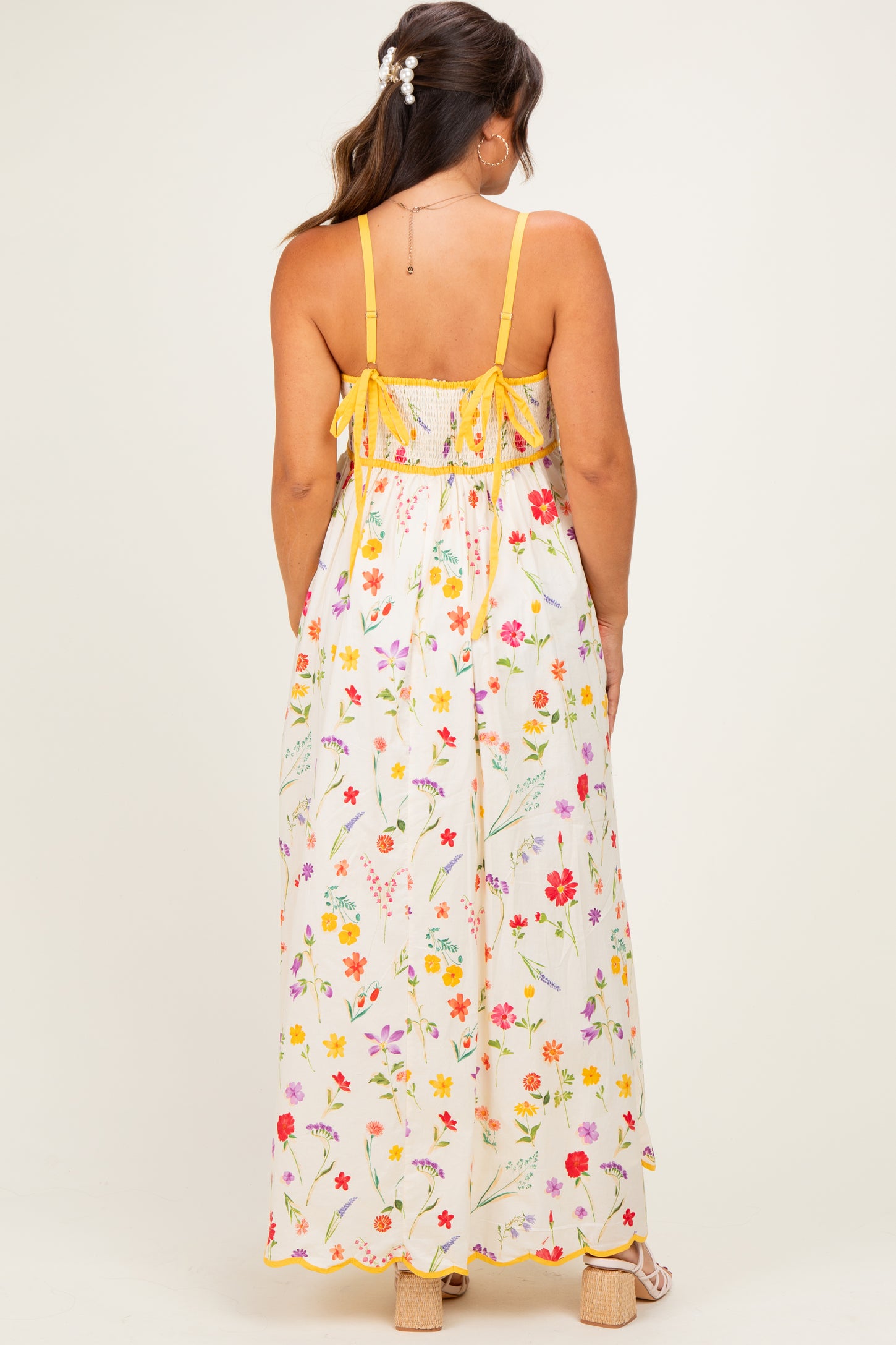 woman wearing a floral print maternity maxi dress with spaghetti straps and adjustable ties at the back