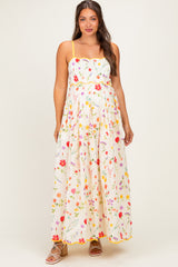woman wearing a floral print maternity maxi dress with yellow straps and a fitted bodice showcasing her baby bump