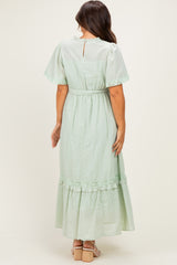 woman wearing a mint green maternity maxi dress with ruffle details and short flutter sleeves, showing the back view