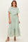 woman wearing a mint green midi dress with flutter sleeves and a tie waist, standing and smiling