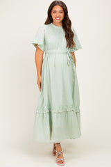 woman wearing a light green maternity maxi dress with short ruffled sleeves and a tie waist detail