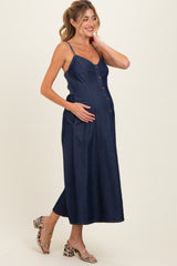 woman wearing a dark denim maternity dress with buttons and pockets, showcasing her baby bump