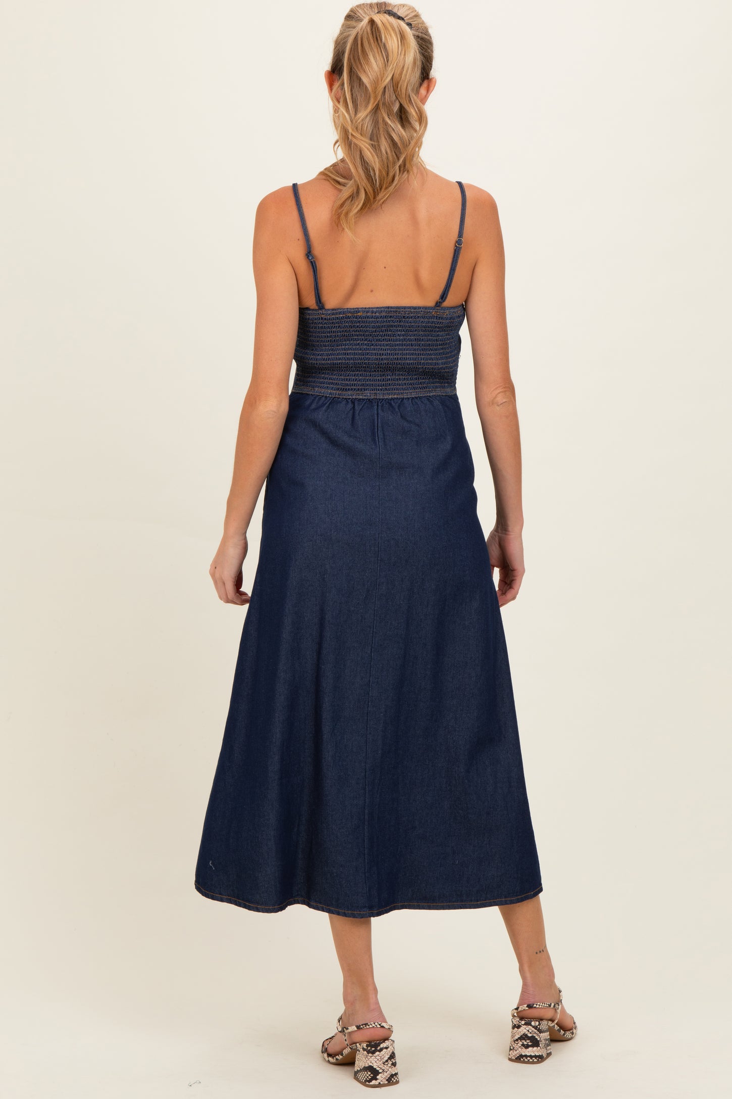 woman wearing a navy blue maternity maxi dress with smocked bodice and adjustable straps, viewed from the back