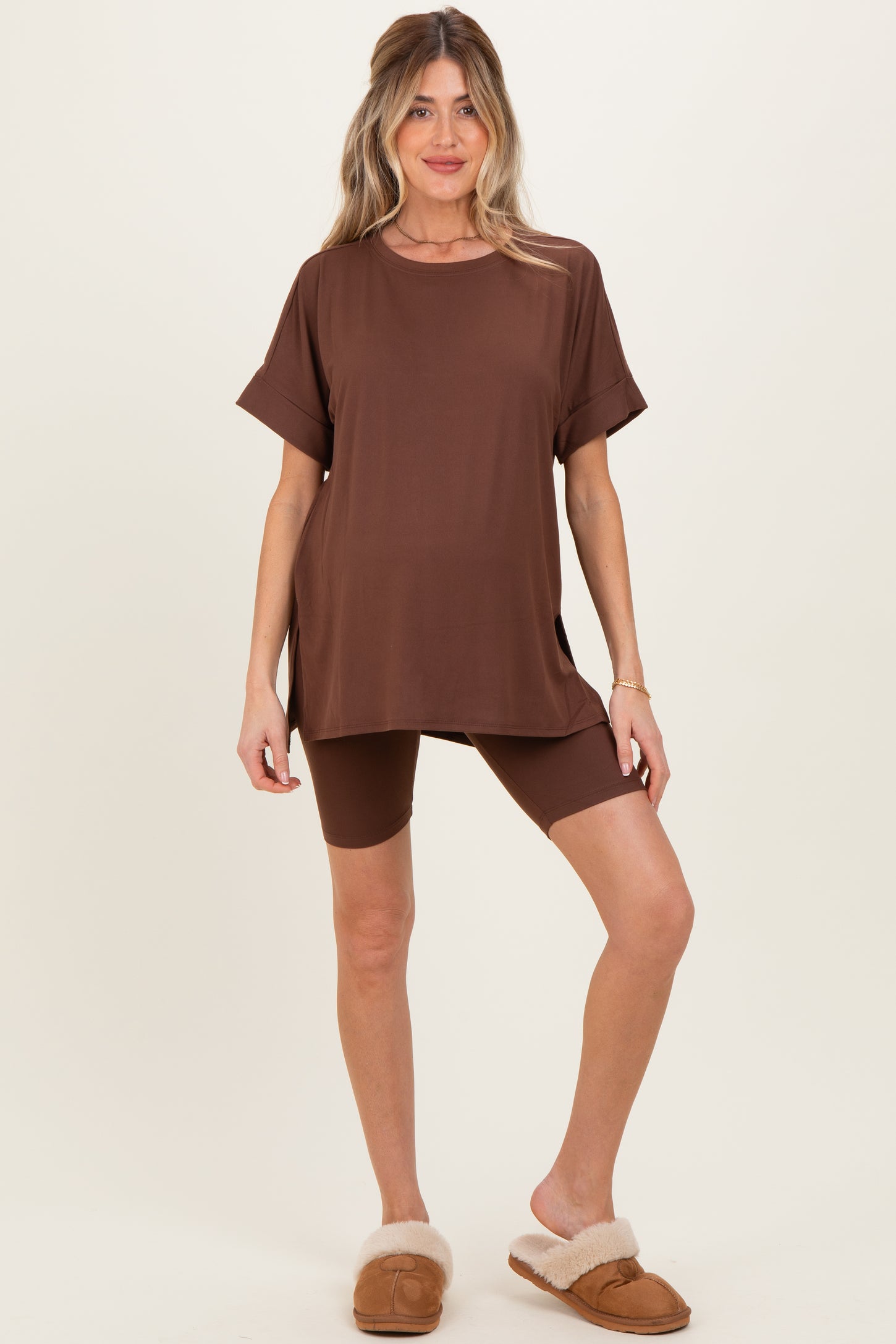woman wearing a brown maternity top and matching shorts, showcasing her baby bump, styled with cozy slippers