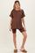 woman wearing a brown maternity top and matching shorts, showcasing her baby bump, styled with cozy slippers