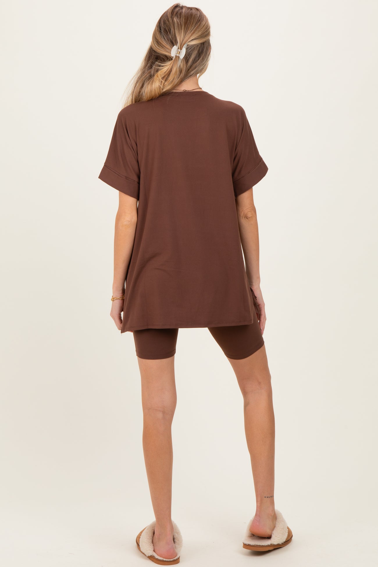 woman wearing a brown maternity oversized t-shirt with matching shorts, standing with her back to the camera