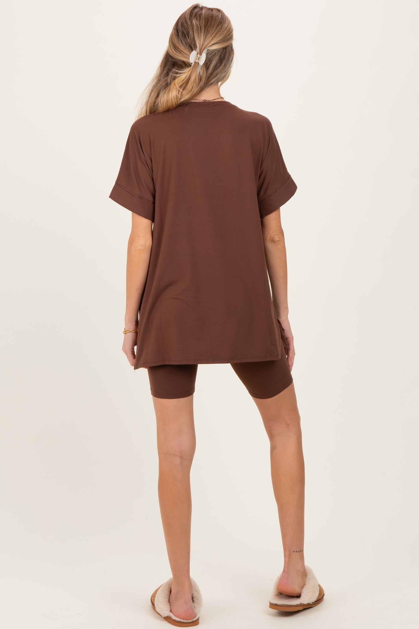 woman wearing a brown maternity oversized t-shirt with matching shorts, standing with her back to the camera