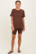 woman wearing a brown oversized t-shirt and matching bike shorts, styled with black flip-flops