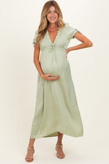 woman wearing a light green maternity dress with lace detailing and holding her baby bump