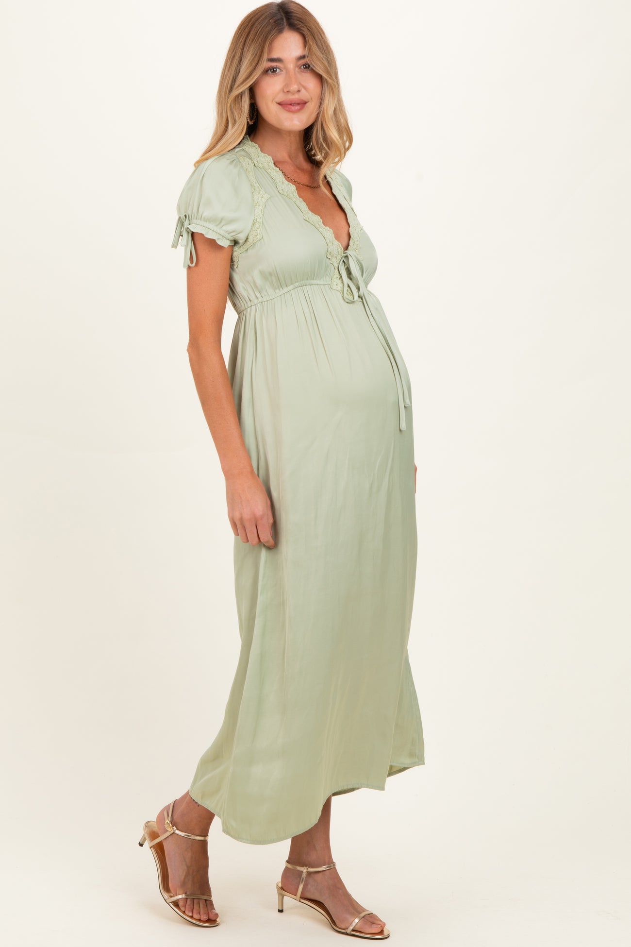 woman wearing a light green short sleeve maternity maxi dress with a tie detail and a visible baby bump